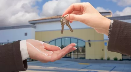Agent Handing Over the Keys in Front of Business Offi