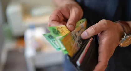 a man's hand holding a wallet and pulling out money from it