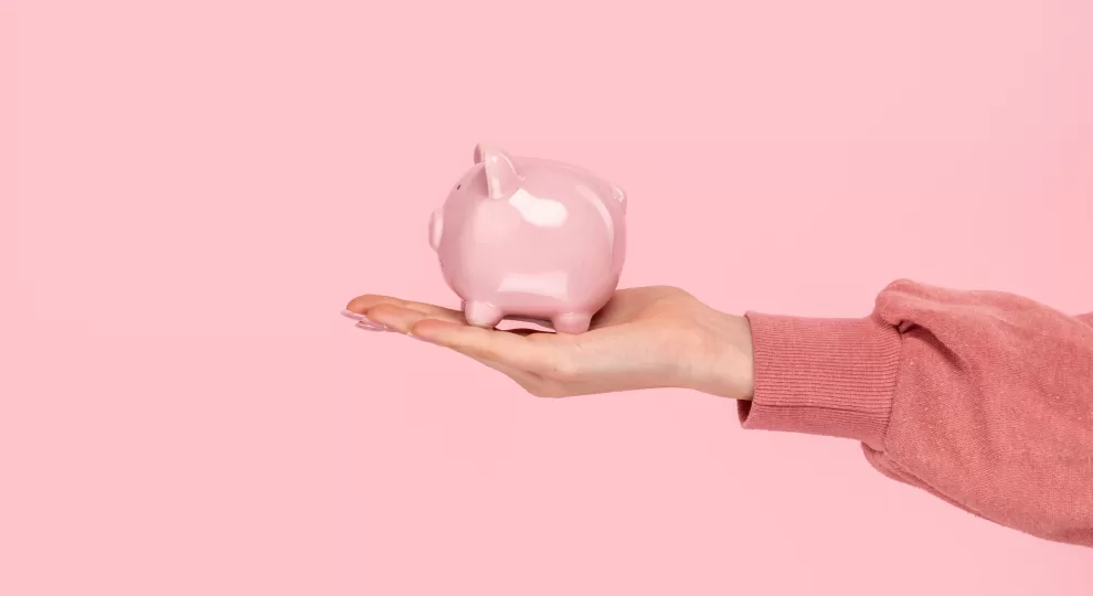 a hand holding a pink ceramic pig