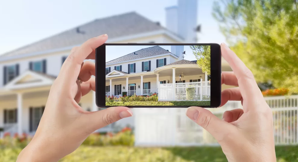 a pair of hands holding a smartphone with a picture of the white house infront of it