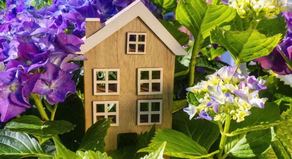 a small wooden toy house surrounded with flowers
