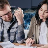 Real estate agent commission by state — Australian home seller working out the cost of selling with a calculator and laptop