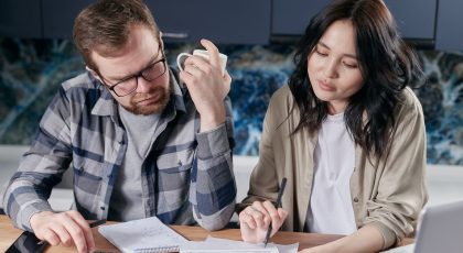 Real estate agent commission by state — Australian home seller working out the cost of selling with a calculator and laptop
