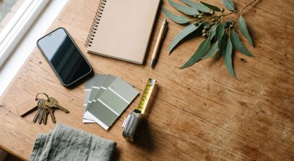 Overhead flat-lay of tools for selling a house yourself, from phone to paint swatches
