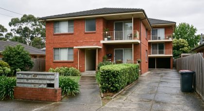 Letterboxes outside a modest Australian red-brick block of rental flats on an overcast morning