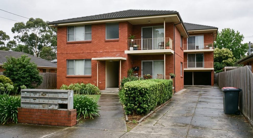 Letterboxes outside a modest Australian red-brick block of rental flats on an overcast morning