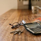 House keys and a calculator on a kitchen bench, representing commission saved when selling privately