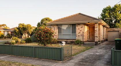 Exterior of a modest Australian brick rental home at golden hour, the sort of property a landlord keeps a rental ledger for